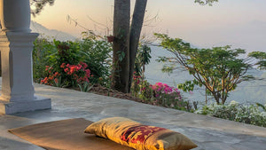 Gruppe beim Yoga Retreat auf einer überdachten Holzterrasse im Sonnenaufgang