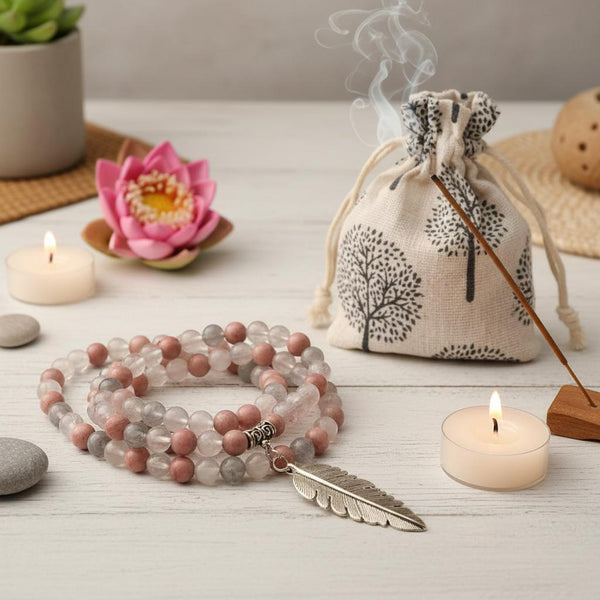 Malakette Rhodonit mit Quarz auf Tisch mit Tasche und Meditationsschmuck